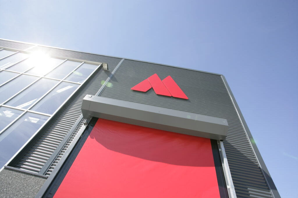 Exterior view of the Aasted headquarters, showcasing the iconic red Aasted logo against a modern architectural facade under a clear blue sky
